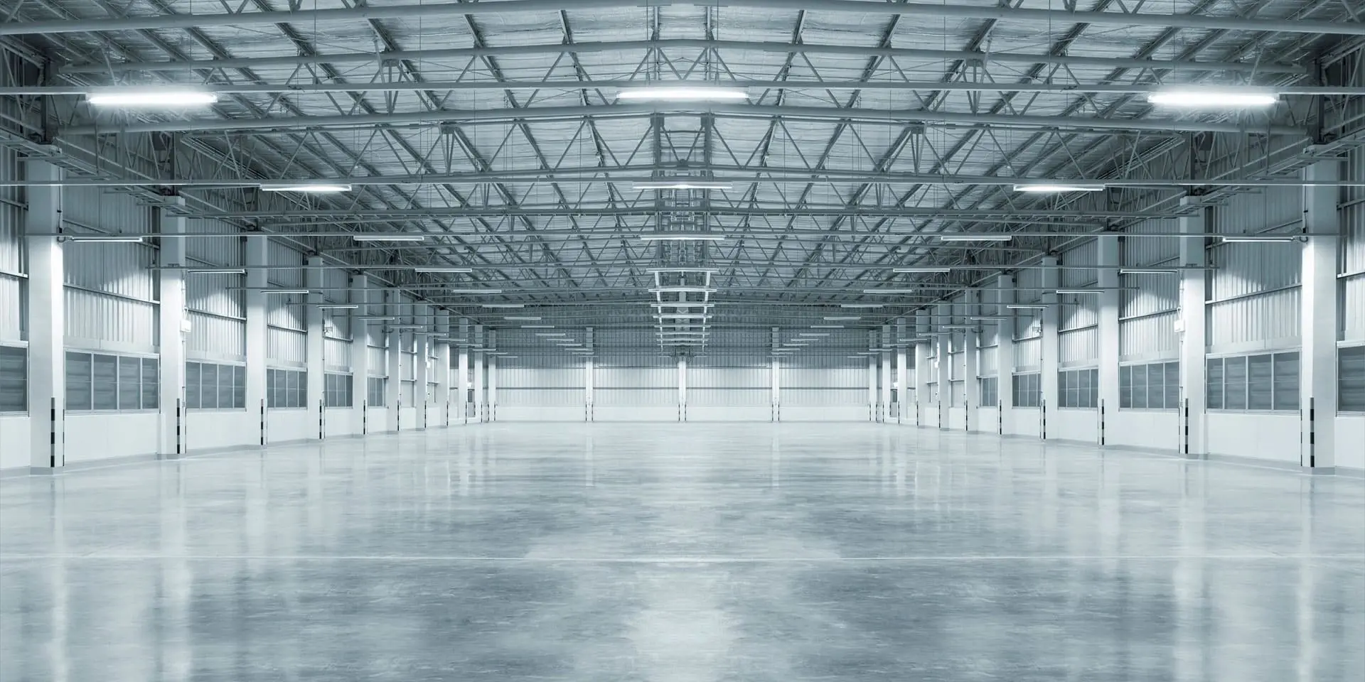 A large empty warehouse with lights on the ceiling.